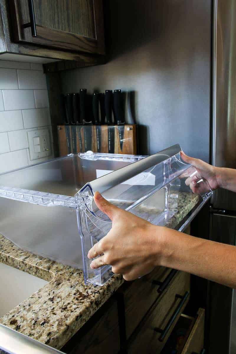 Putting the front of the refrigerator drawer back on while doing a refrigerator cleaning