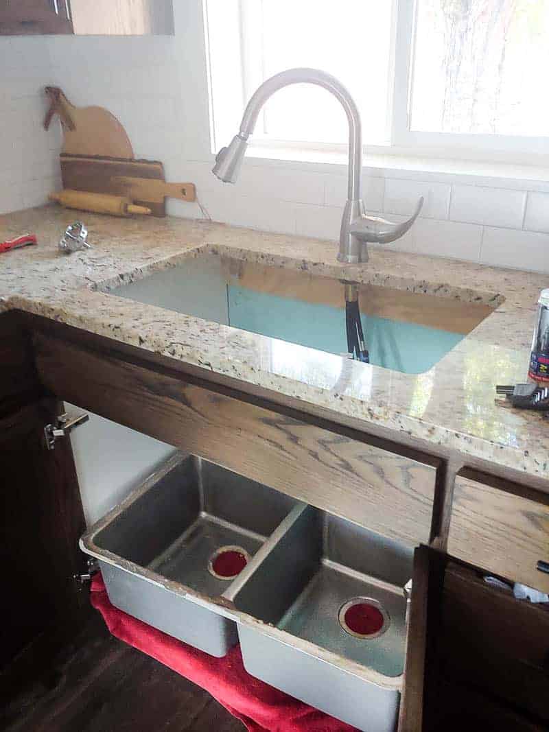 During a kitchen renovation, an undermount sink is removed from a granite countertop basin