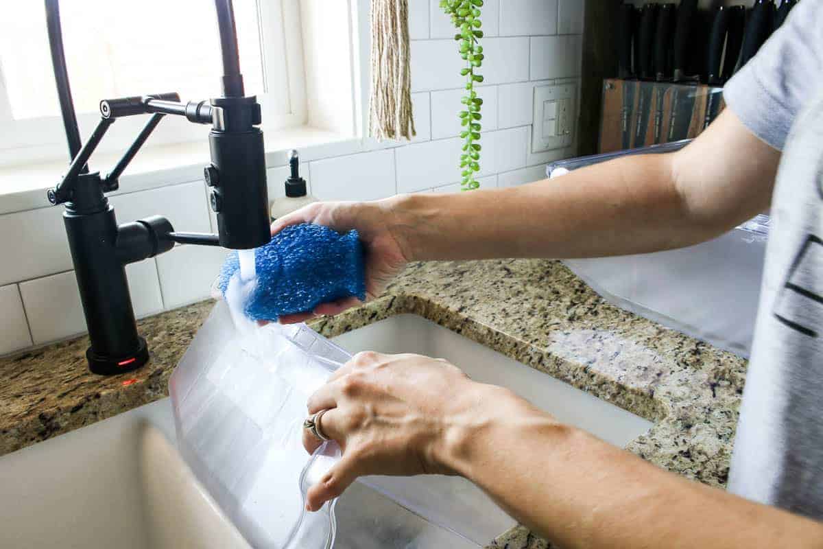 Washing the refrigerator drawers in the kitchen sink with the DishFish scrubber sponge