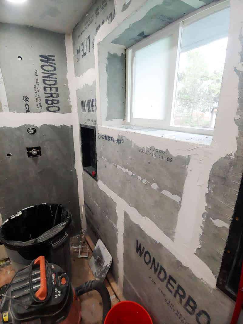 This bathroom renovation is in progress, with drywall around a window and line paint