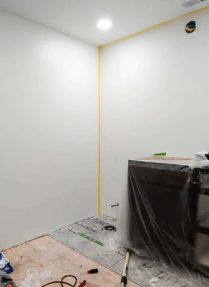 White walls in ensuite bathroom under a renovation with an accent wall taped off on the edges with FrogTape painter's tape