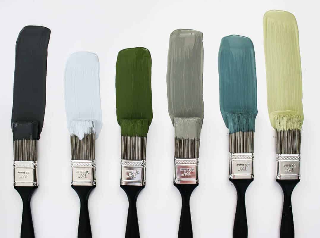 Nature inspired colored paint samples against a white background with paint brushes