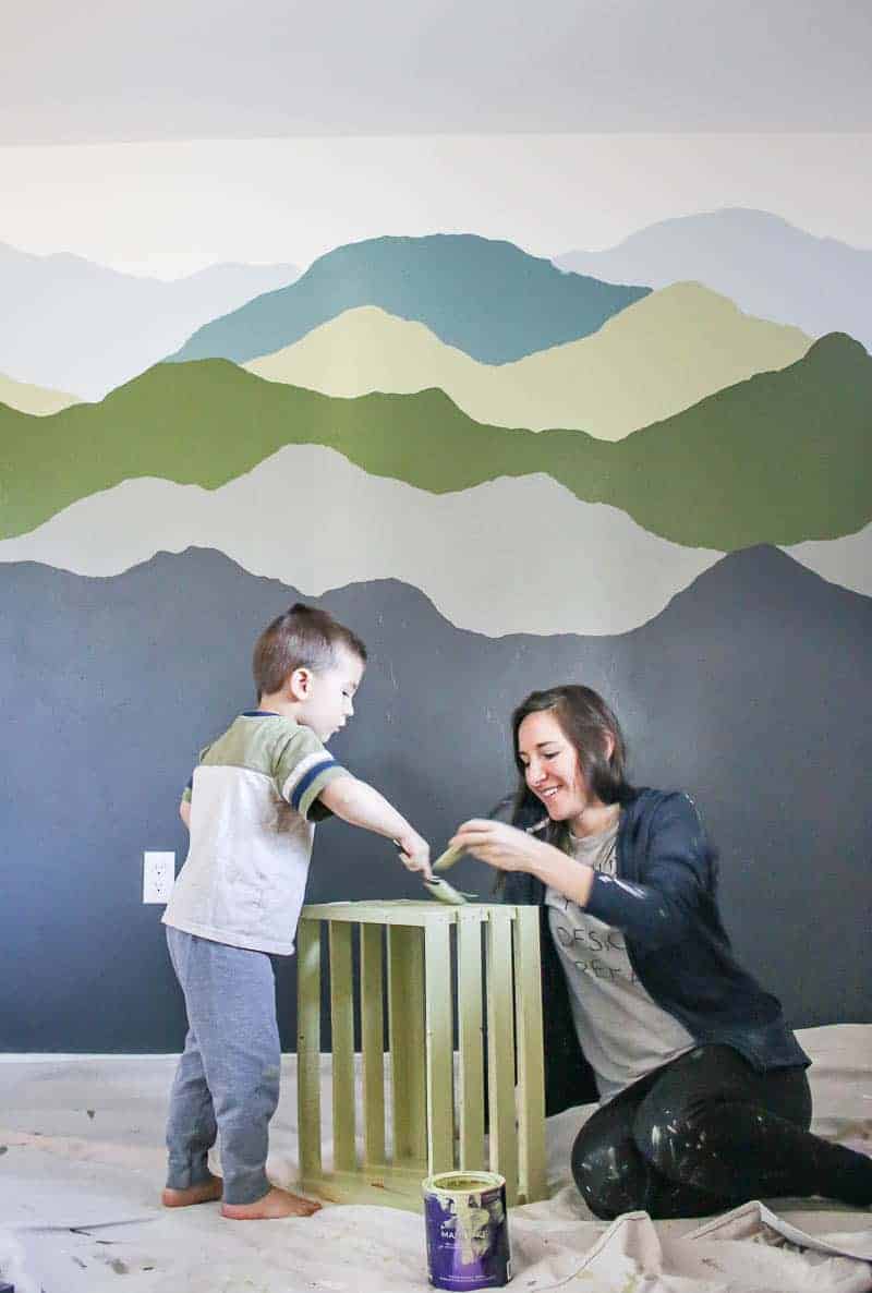 Painted wall behind the mother and son painting a wooden crate