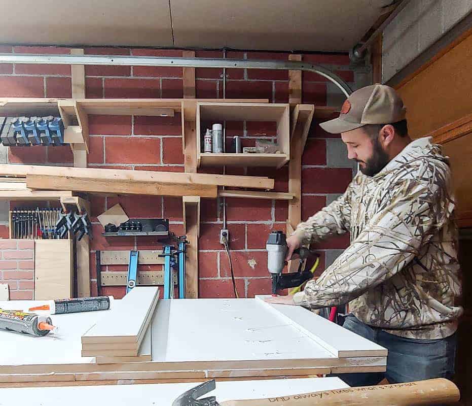 Here is Logan, using a nail gut to attach the wooden slats to the large white barn door.