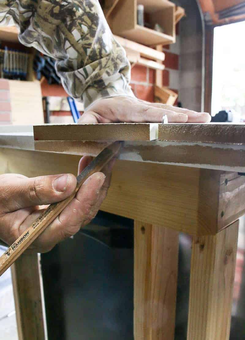 A pair of hands marks the back of wooden slats using a pencil.