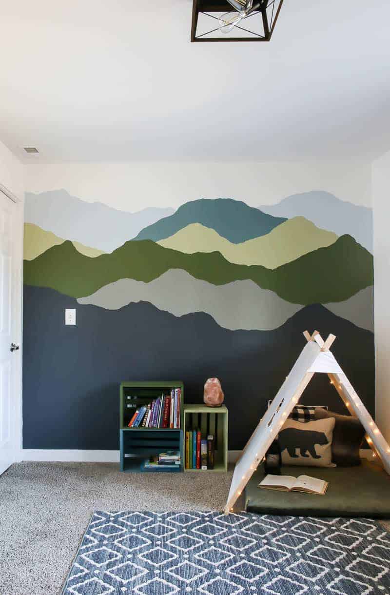 Full view of the mountain mural paint, colorful pallet bookshelves and cozy nook for the boys new room.