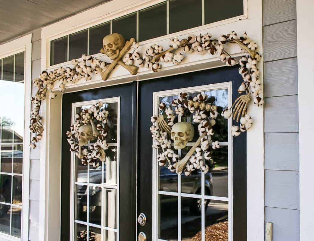 Two wreaths for each door with skulls and a garland on top of the front door.