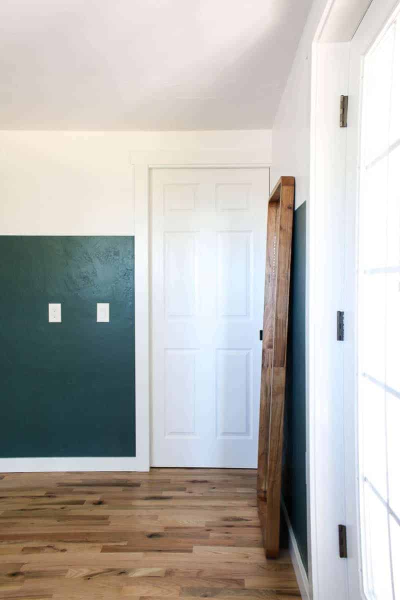 The entrance door to our master bedroom, two toned walls painted white and jade green, and a tall mirror leaning against the wall.