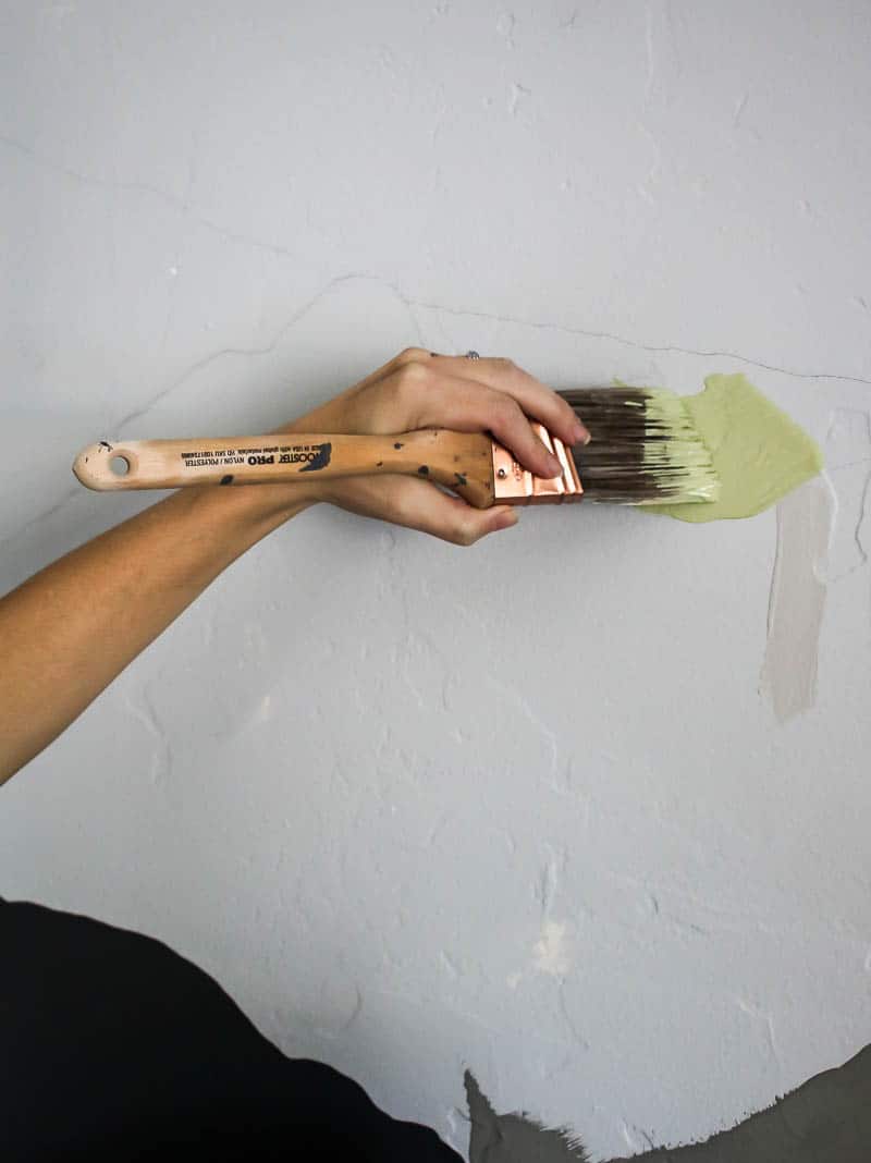 Painting a small section of the mountain mural with an angled paint brush