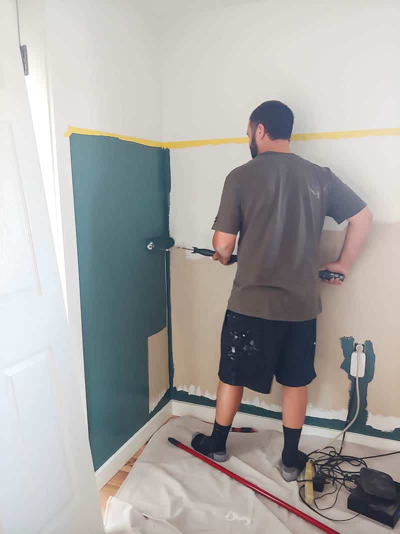 Logan is painting the bottom half of the two tone walls in our bedroom with a deep jade color paint. We're using Frog tape to ensure we're painting straight lines.