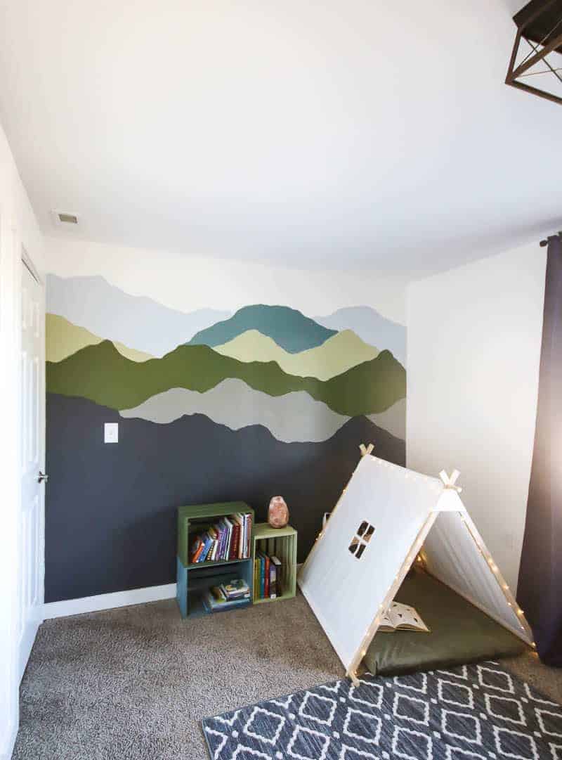 Woodland boys room with painted wall, colorful pallet bookshelves and a nook.