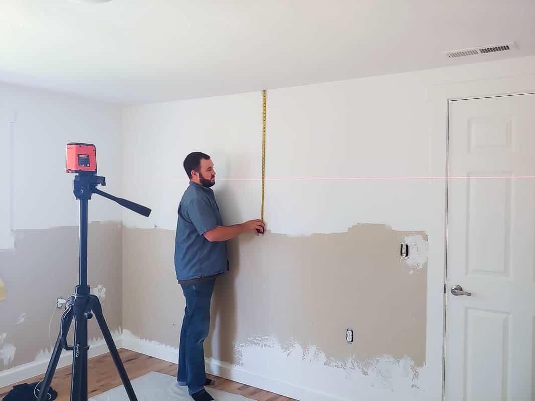 Using a level to measure out the two toned walls in our master bedroom; half the walls are painted white, the lower half remains unpainted.