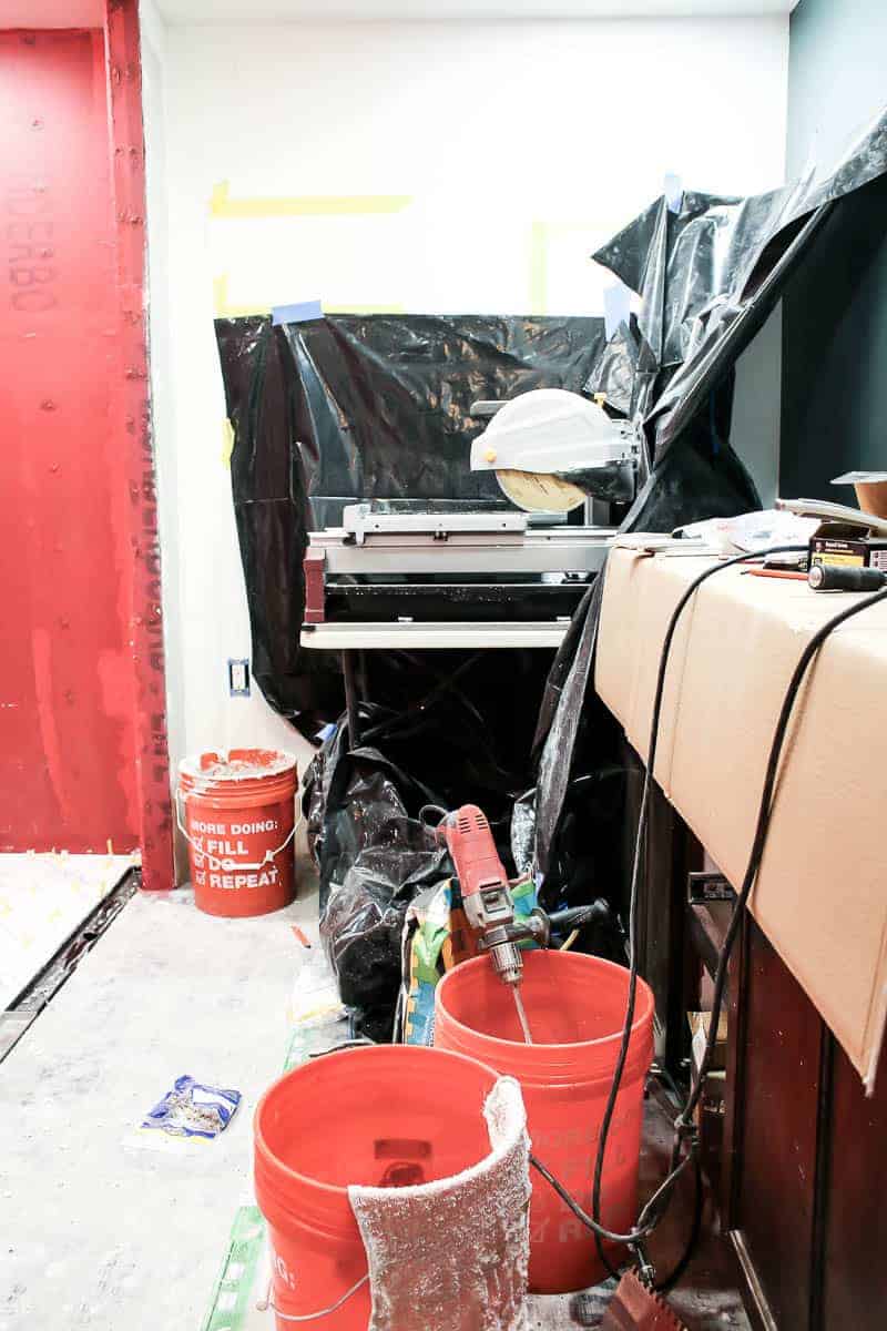 A wet tile saw set up in our master bathroom during the bathroom renovation project, surrounded by construction supplies.