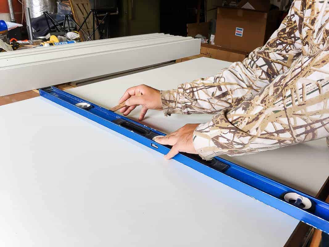 Measuring the center of the white primed MDF sheet to build a barn door on a budget.