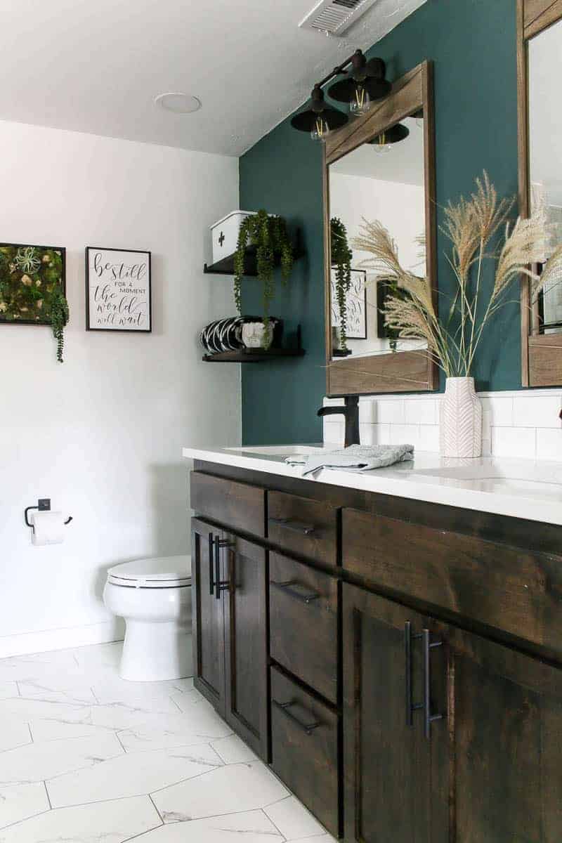 Side view of the vanity showing mirrors, white countertop, hanging shelves and toilet bowl.