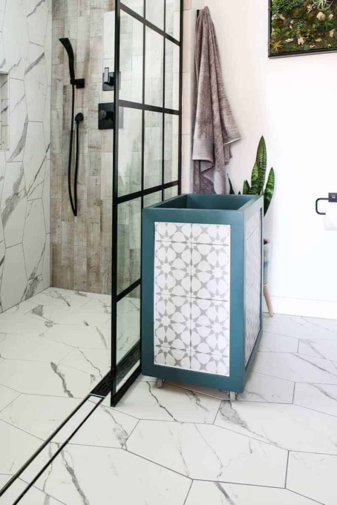 this diy wood laundry hamper with a tile inlay has castor wheels for easy transportation to and from the laundry room