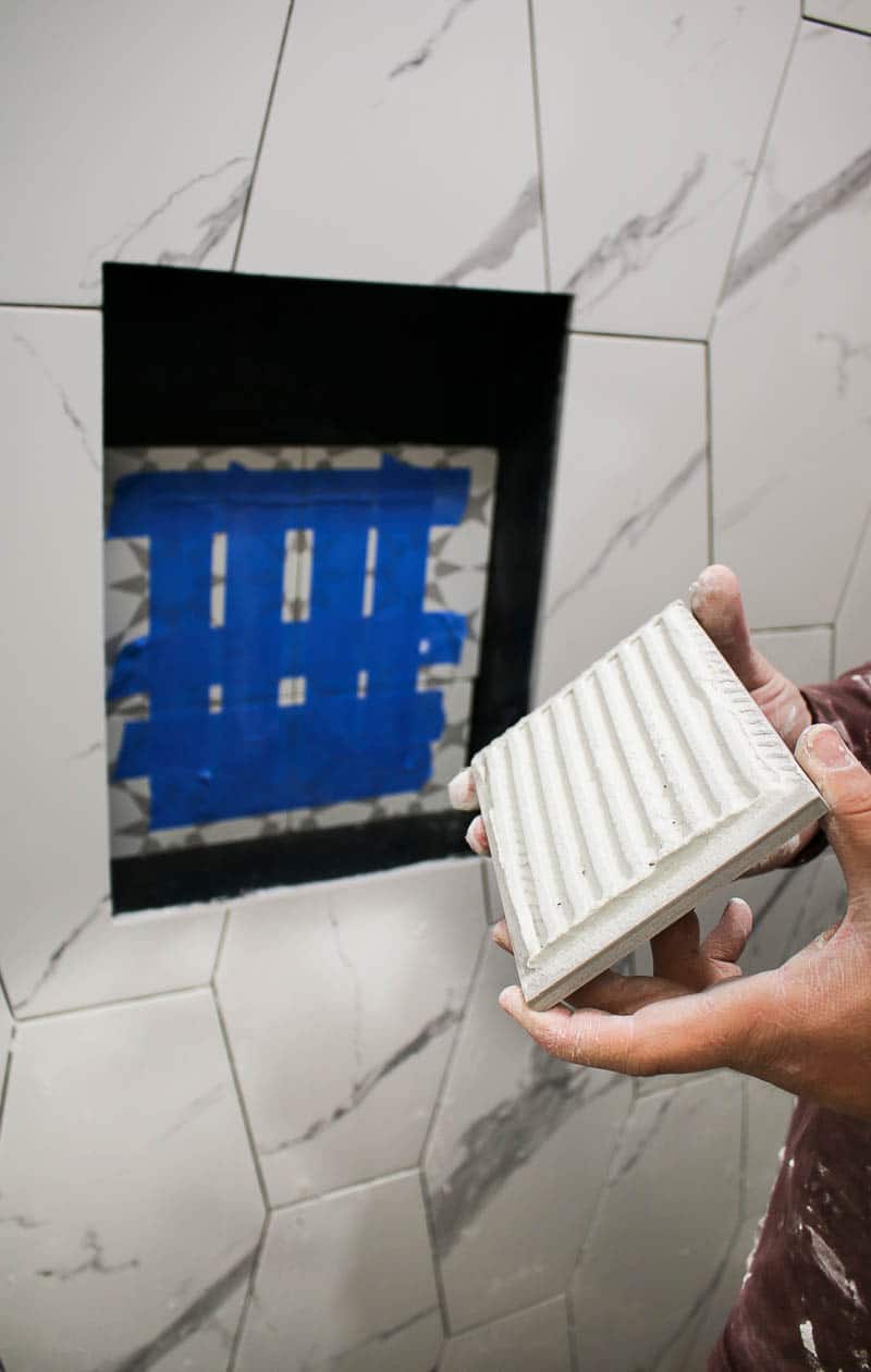 Man holding a tile ready to be installed on the bathroom wall