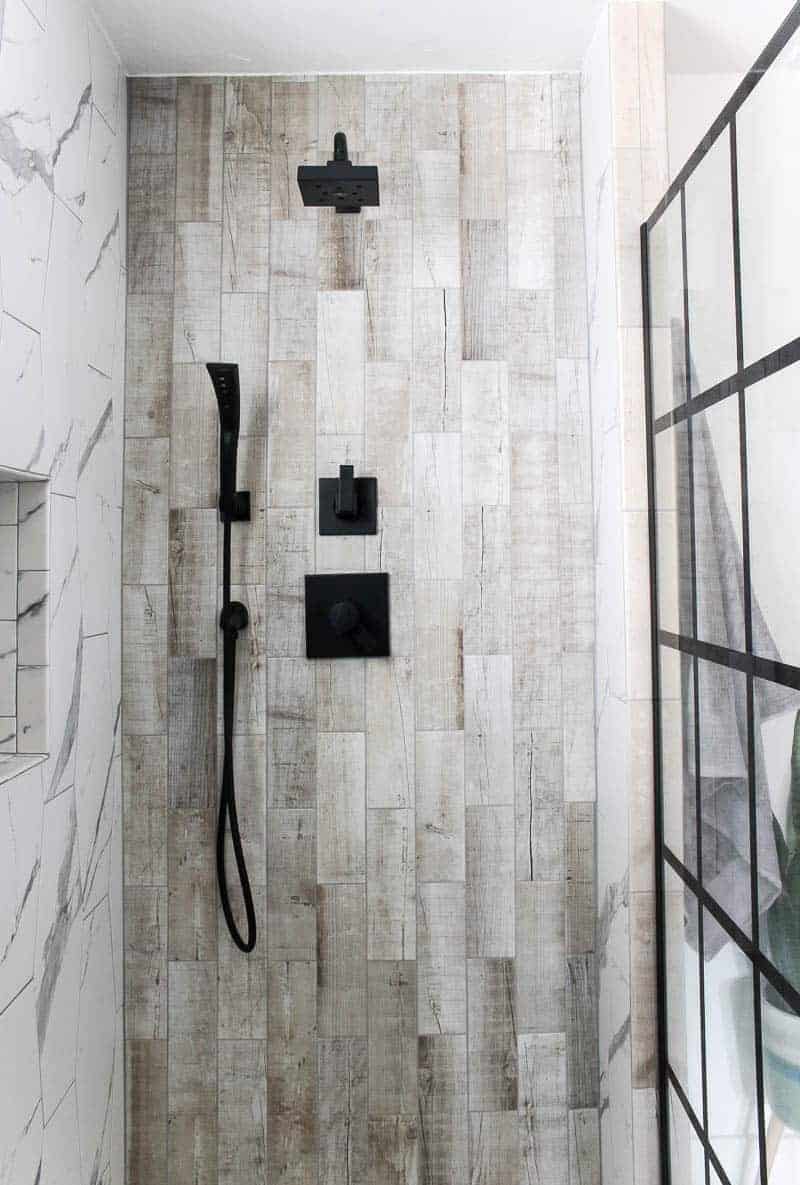 Shower area with wood look tile and black shower head and faucet