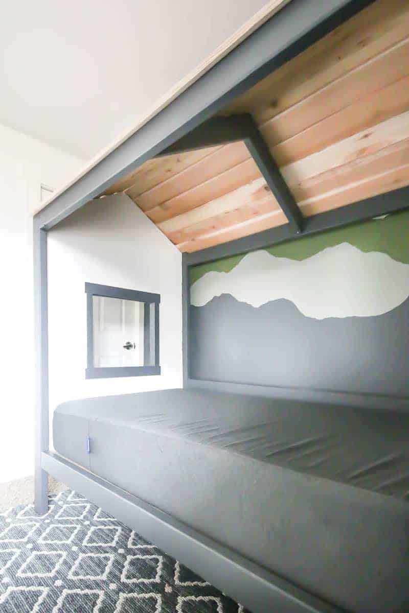 A look at the inside detail of our DIY kid's cabin bed, with a window and gray bedding.