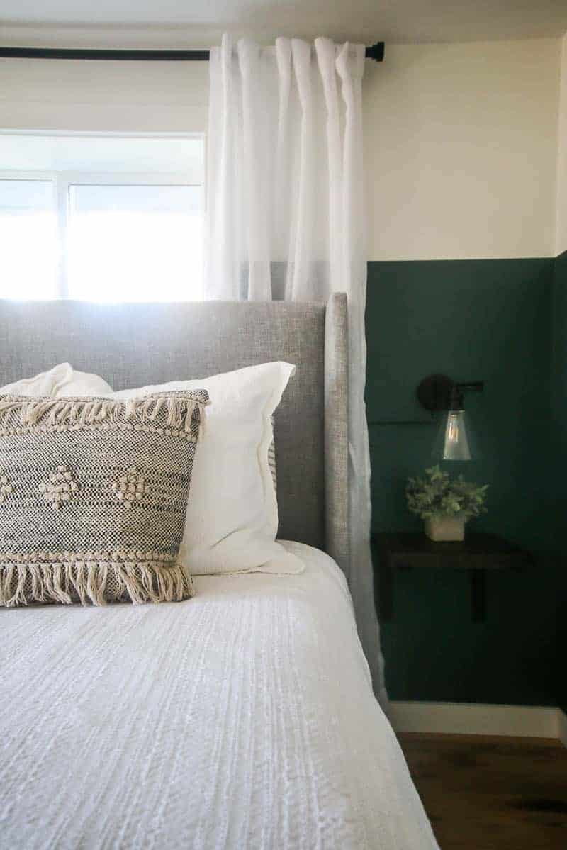 Half of our new green boho bedroom - dressed in soft white linens and accented with bohemian style throw pillows.
