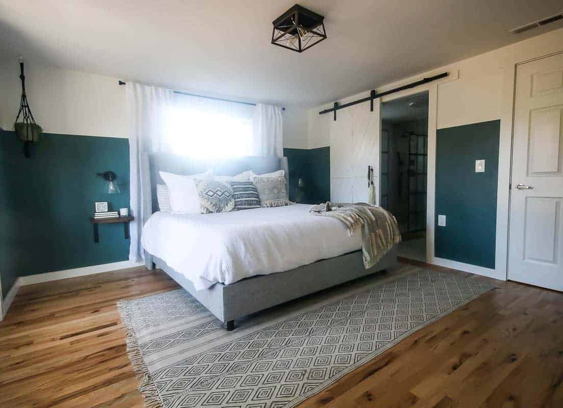 A full view of our green boho bedroom makeover, including our new king size bed, our stunning master bathroom and DIY barn wood bathroom door, and new geometric metal bedroom light fixture.