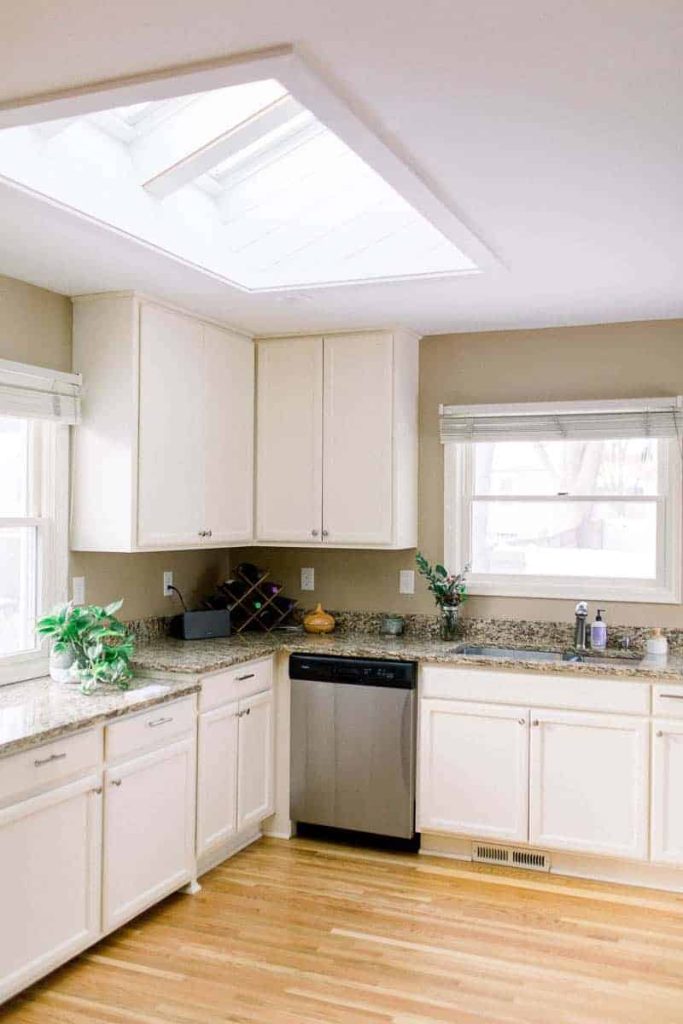 A modern kitchen with white cabinets, granite counter tops, bright windows and wood floors
