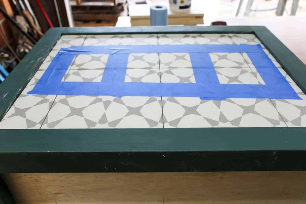 Use painters tape to hold the tiles on your diy hamper in place while the tile inlay dries