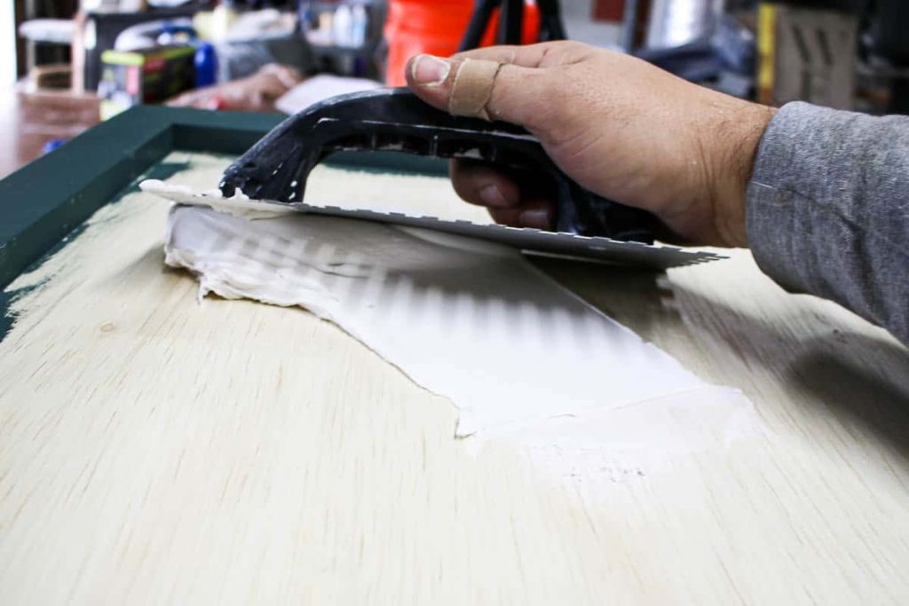 Applying tile adhesive to the top and sides of our diy hamper