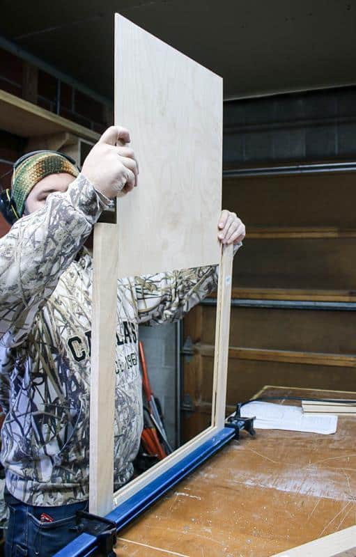 The man continues assembling the sink cabinet.