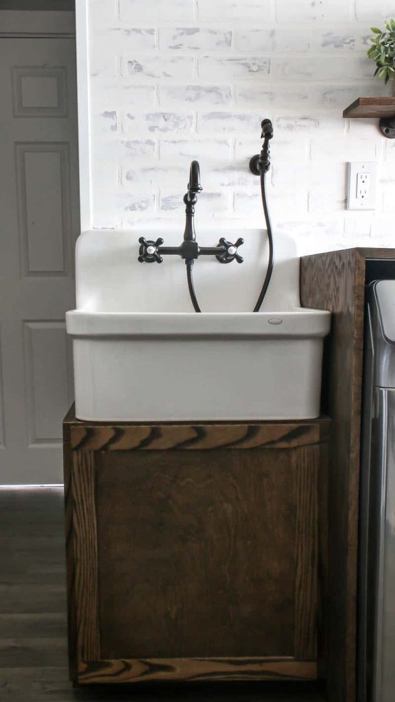 A large farmhouse laundry room sink and cabinet, with a vintage style faucet and detachable sprayer