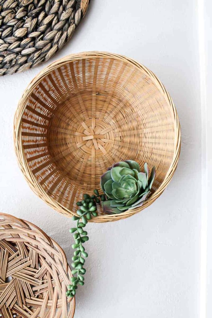 This wicker basket has a small succulent accent, bringing a touch of green to the neutral wicker basket wall