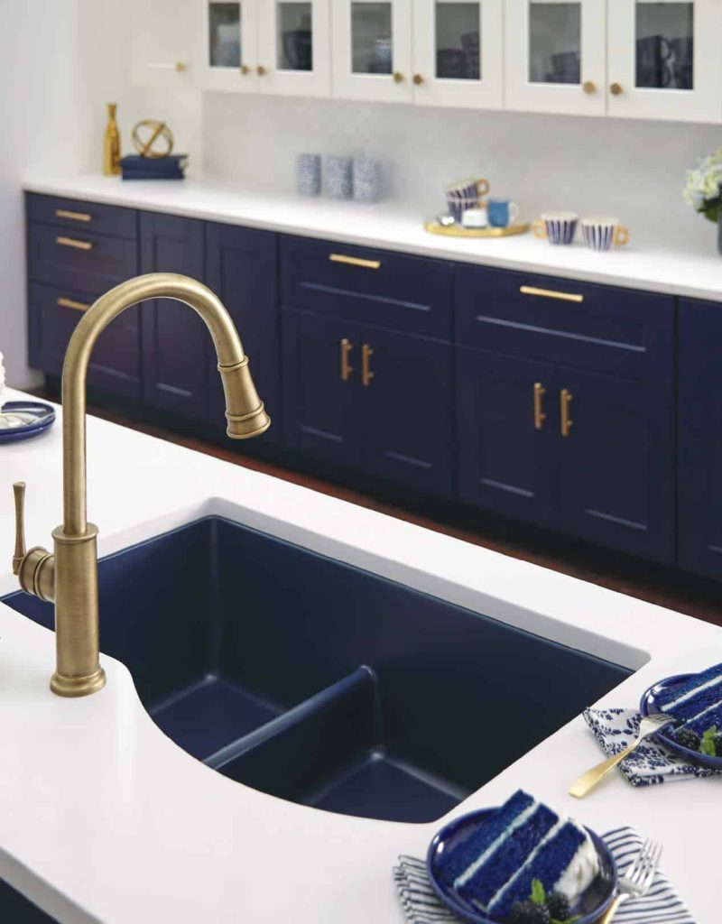 A modern blue inlayed kitchen sign with white countertops and gold fixtures