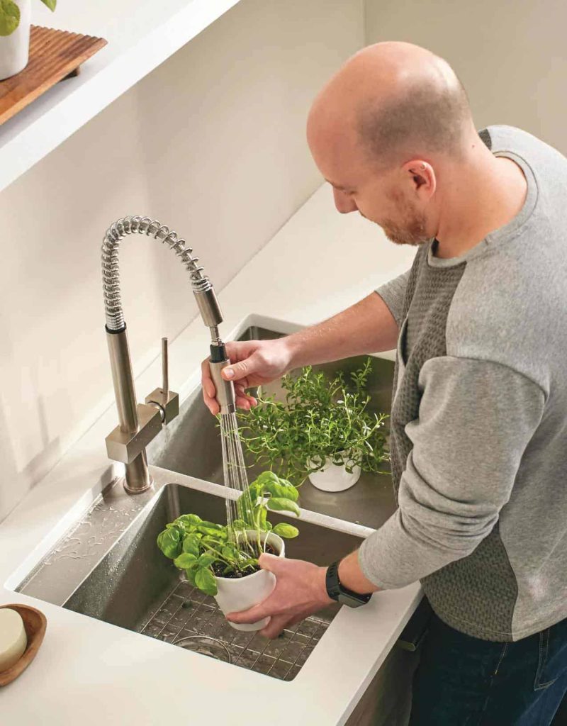 A stainless steel kitchen sink with white countertops and stainless steel fixtures