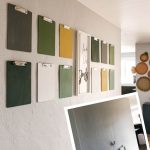 shows 12 gray, green, white, and yellow clipboards on a gray wall with a white live life simply frame in between the clipboards with a before picture of a blank wall