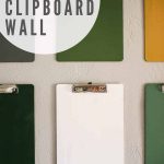 shows an up close picture of the colorful clipboards on a gray wall with overlay texts that says colorful clipboard wall