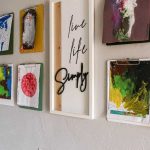Colorful kid's paintings hanging on clipboards in the hallway