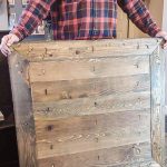 Man holding wood tabletop upside down you can see the bottom side with pocket hole joinery