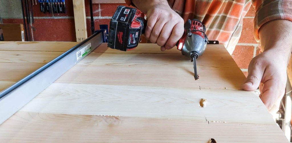 The man is assembling the table slats onto the kitchen table top, completing the construction process.