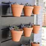 shows a side view of 9 vertical garden pots with succulents hanging on a black wood wall mounted on the side of a gray brick house with overlay texts that says DIY plant wall