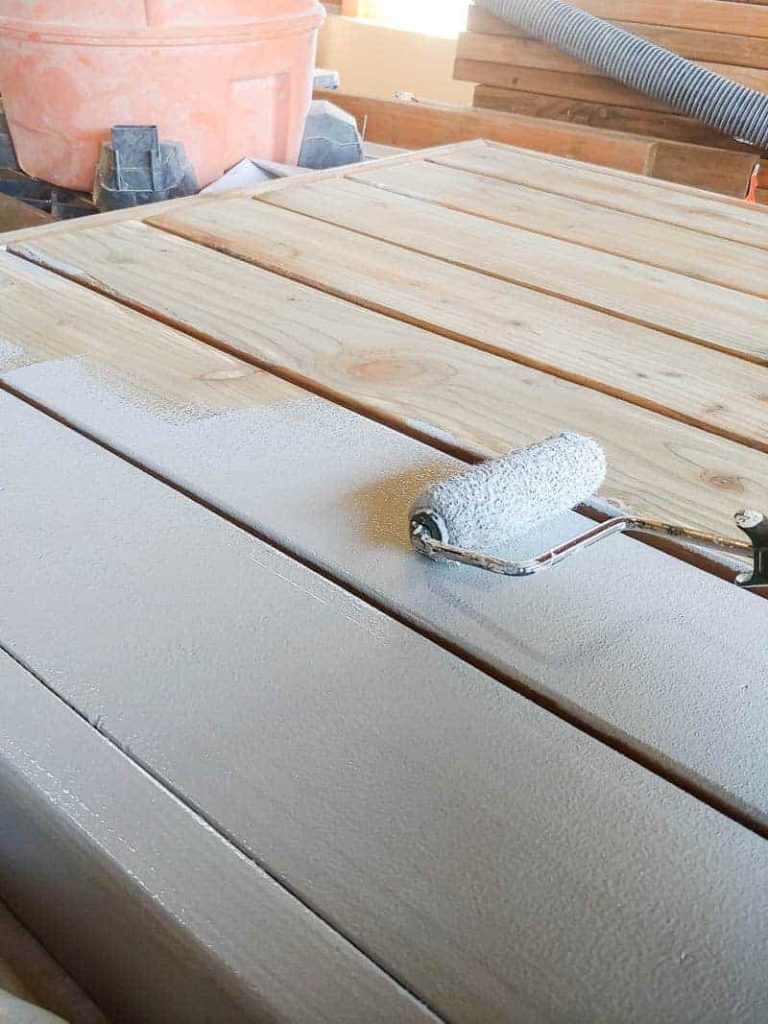 shows a wood pallet getting primer on it with a roller