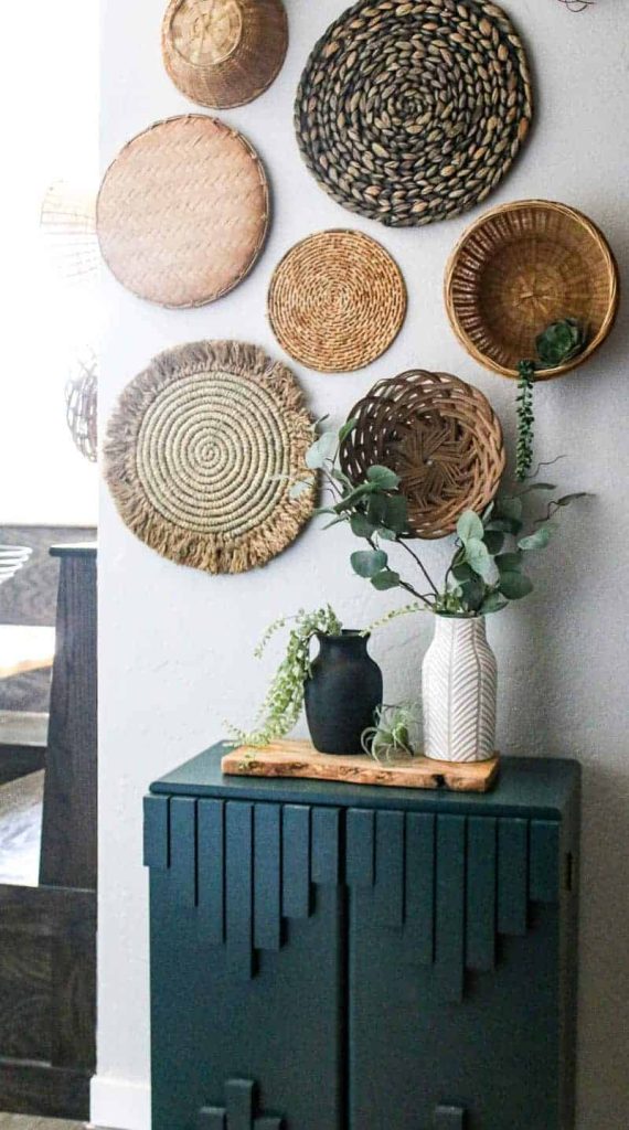 Black and white vintage vases sit on a cabinet under a wicker basket wall. 