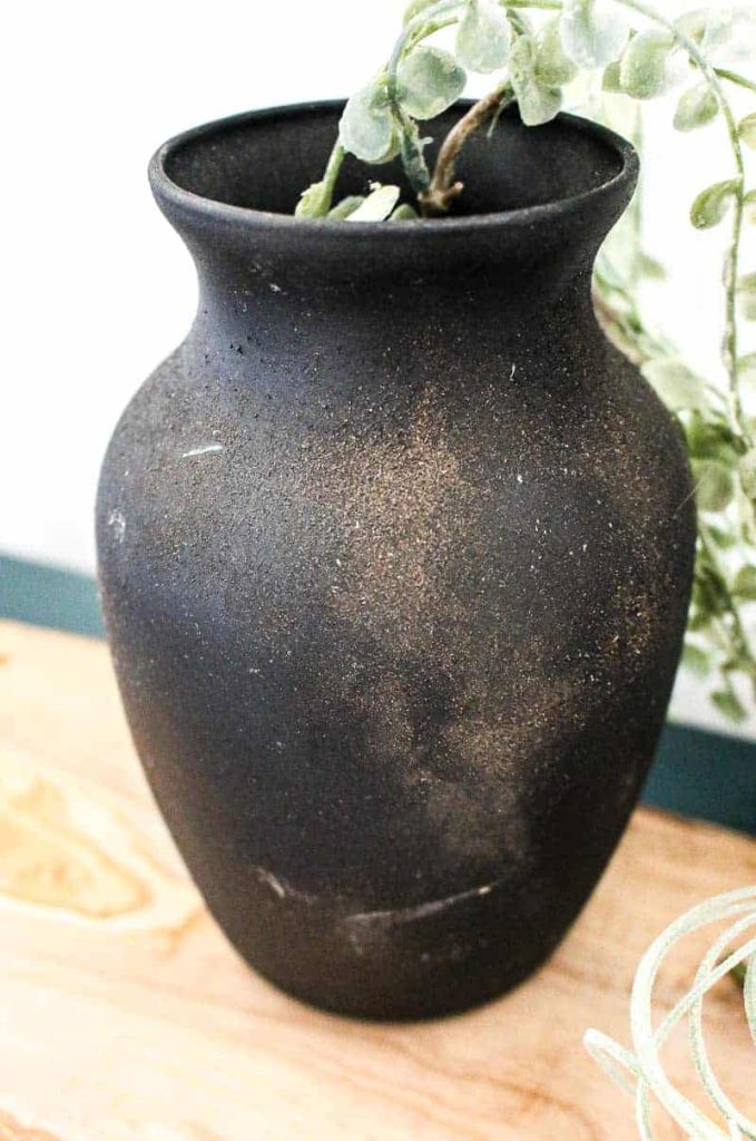 A close-up look at the vintage pottery effect on this upcycled vase. We painted this vase black and tossed some fine, sandy dirty on the wet paint, creating a pottery-like finish on the vase.