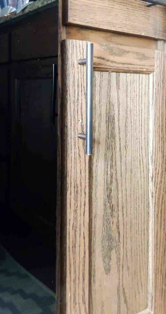 A stained wood cabinet door has a small nail hole where the old cabinet hardware was attached. Here's how to easily repair nail holes in stained wood.