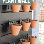 shows a side view of 9 vertical garden pots with succulents hanging on a black wood outdoor plant wall mounted on the side of a gray brick house with overlay texts that says how to build a plant wall