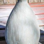 shows a vase covered in joint compound drying outside on a wood pallet