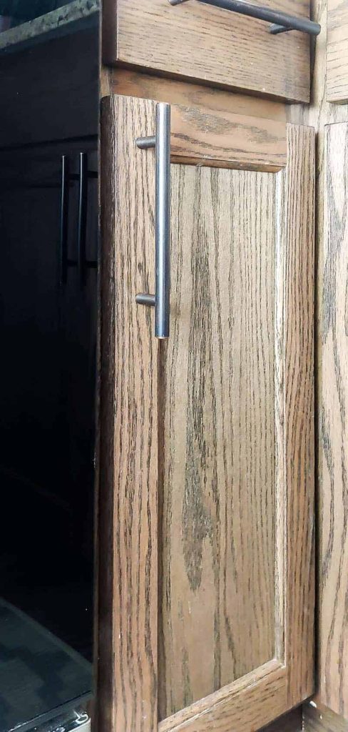 A stained wood cabinet door with new brass hardware. We filled a nail hole on this stained wood door using Mohawk wood repair products, and now the nail hole is barely visible!