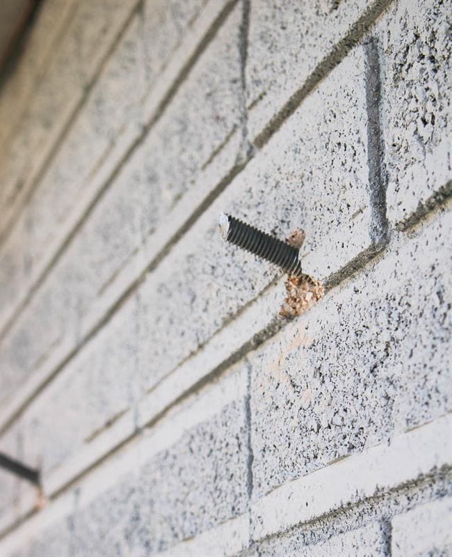 Steel rods in brick exterior to hang vertical plant wall on house