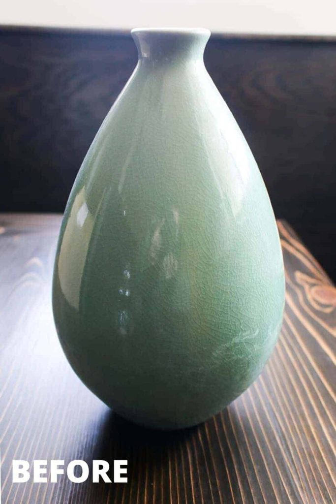 An ombre green ceramic vase sits on a wood table. Learn how to turn this thrifted vase into a classy, vintage style piece of pottery!