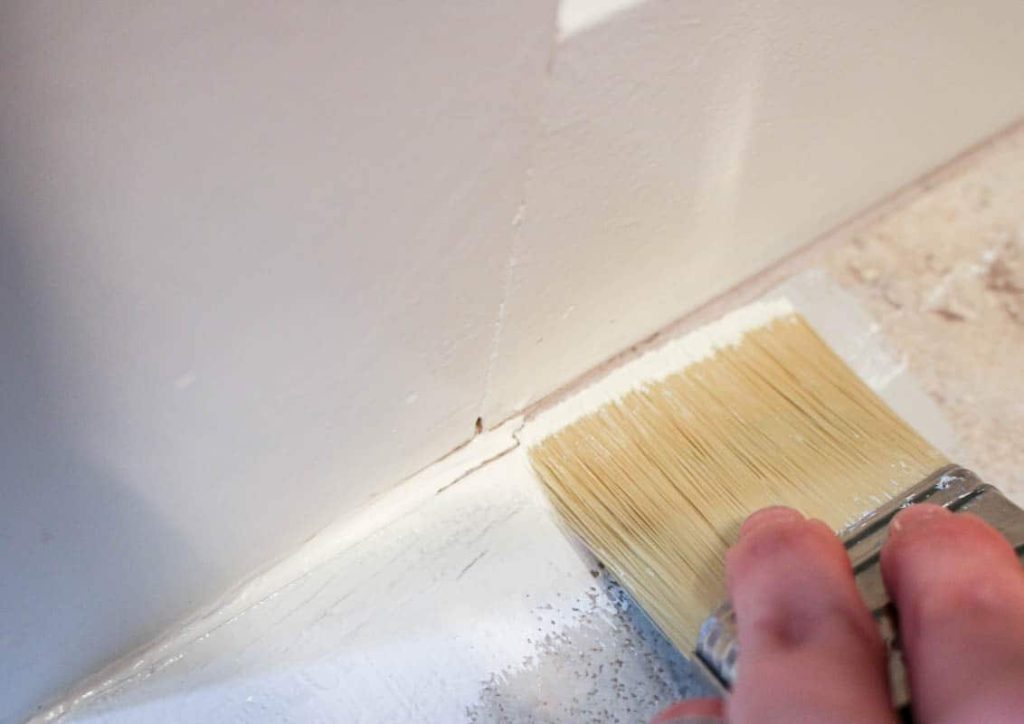 Start painting tile flooring across the edges of the floor, using a paint brush to prep for stenciling floor tiles