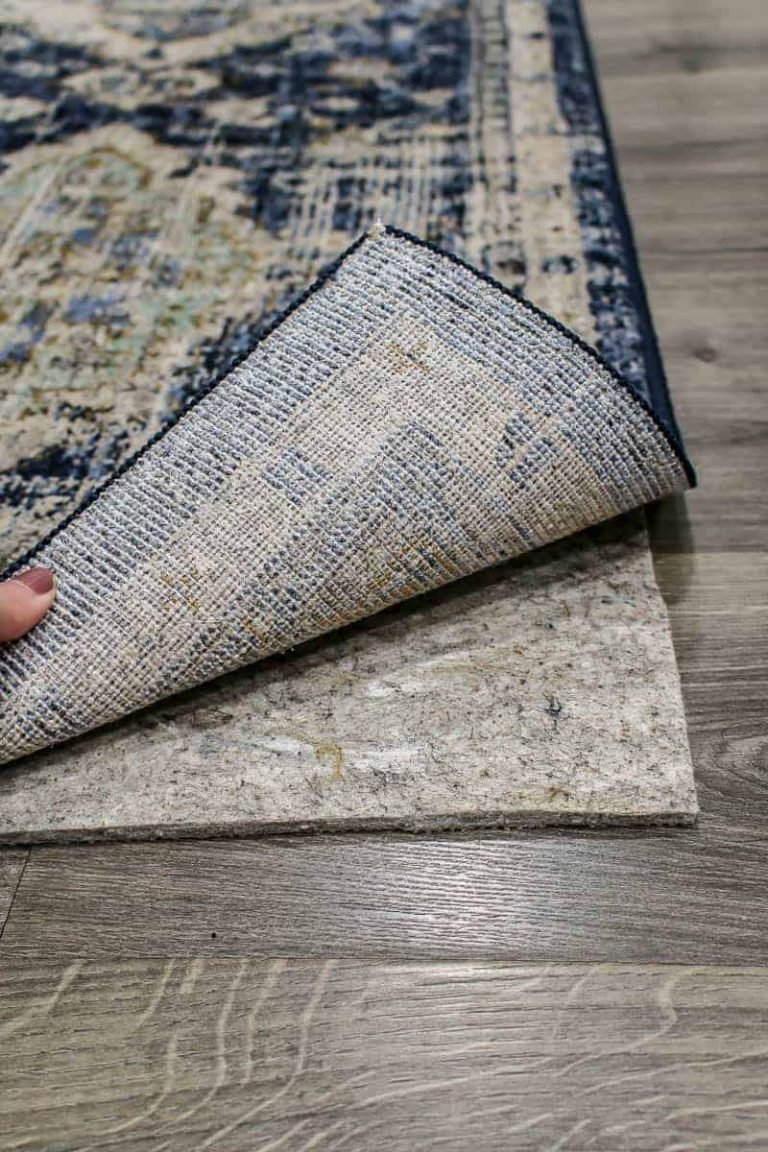 shows the Pantaleone Indigo Runner Area Rug being lifted up to shows a rug pad on gray wood floors